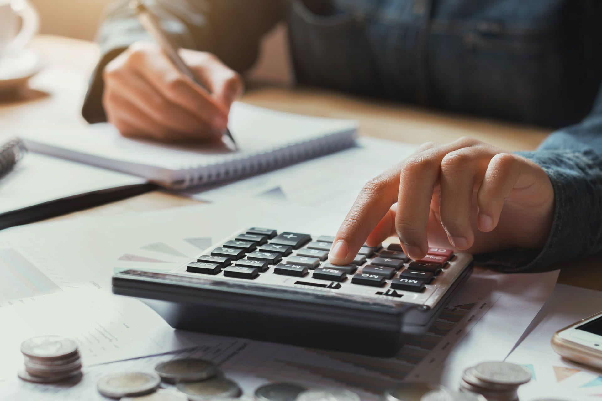 Persona haciendo cálculos con una calculadora y anotándolos en una libreta